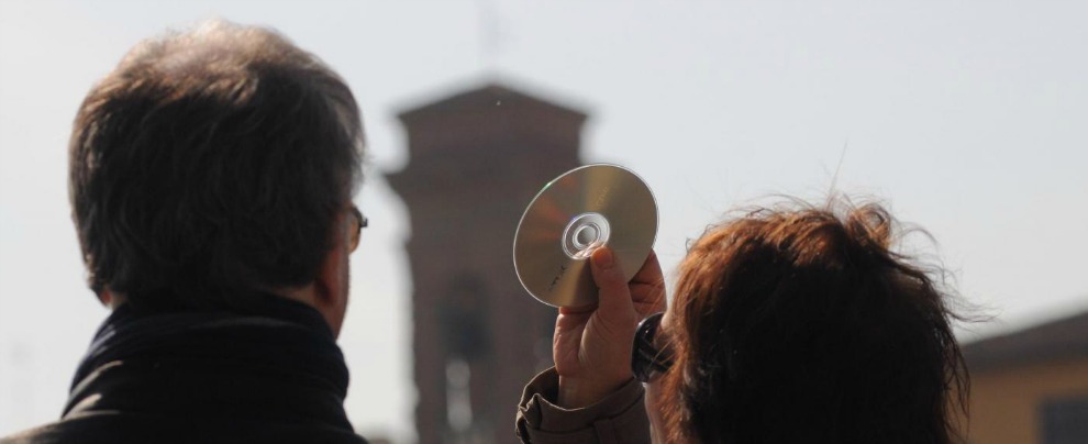 Una donna guarda l'eclissi attraverso un CD