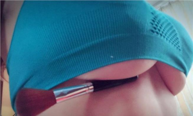 Seno che sorregge pennello per make-up